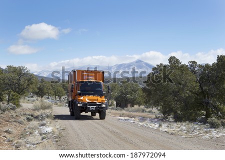 WILD RIVERS RECREATIONAL AREA, NEW MEXICO, USA - April 15: Custom orange RV truck driving on snowy dirt road on April 15, 2014 at Wild Rivers Recreational Area, New Mexico, USA.