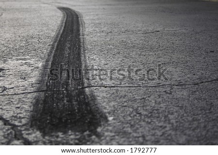 A rear tire burnout or skid mark on old cracked asphalt.