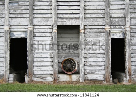 A closeup of the front of an old corn crib, with a dryer exhaust fan