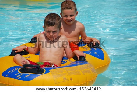Two brothers ride the tube through the water on a hot summer day