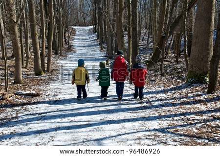 Band of boys follow the snow covered path through the woods