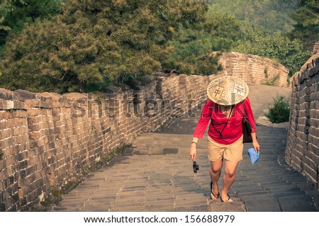 A young woman climbs the arduous steps of the Great Wall of China.