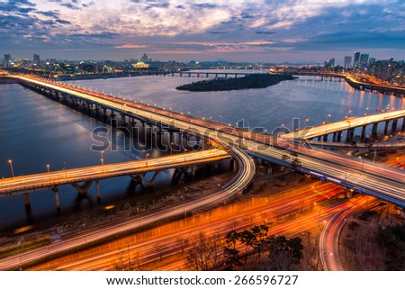 Traffic blurs across a bridge on the Han River as dusk settles in over Seoul, South Korea.