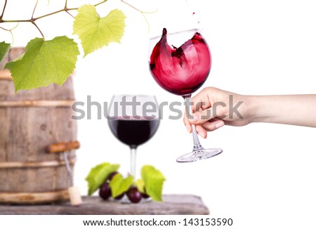 Red wine, glass barrel with grapes hand with glass over white