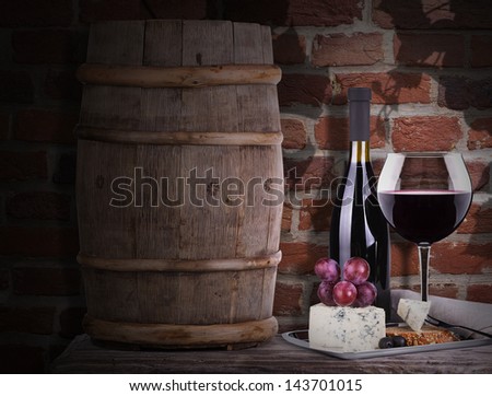 grapes on a barrel with corkscrew, wine glass and cheese  against grunge brick wall background