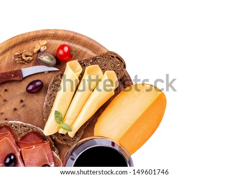 picnic lunch on a wooden board including a wine,bread,cheese,olives,jamon and grapes