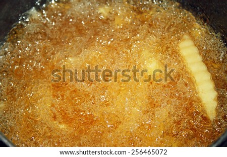 French fries cooking and bubbling in a deep fryer filled with oil