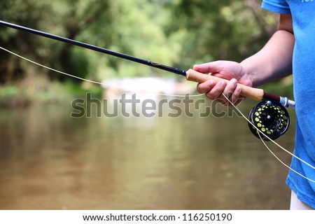 fly fishing rod in hand.