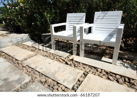 white wooden chairs in garden with stone pathway