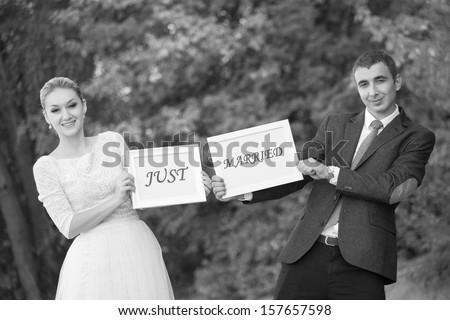 happy Groom and Bride in a park with signs