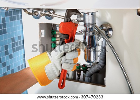 Plumbing work and sanitary engineering repairing a pipe under a sink. Sanitary works. Plumber repairing
