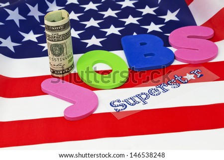 Letters spelling JOBS placed on American flag with currency and Superstar in glitter letters emphasizes critical nature of employment in today\'s economy and financial environment.