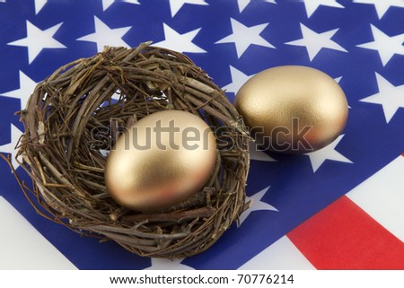 Two, gold eggs, one in twig nest and one directly on American flag, depict the financial building of personal as well as national prosperity