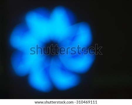 Blurred and out of focus image of an abstract blue shapes closeup of the glowing neon lights on a black background
