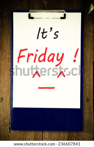 It\'s Friday - Hand writing text on a piece of paper on wood background