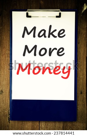 The phrase Make More Money typed on a piece of note paper and pinned to a cork notice board