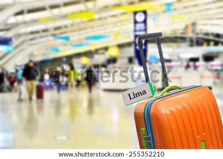 Lima, Peru. Orange suitcase with label at airport.