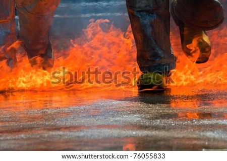 Two men in firefighting suit walking on fire