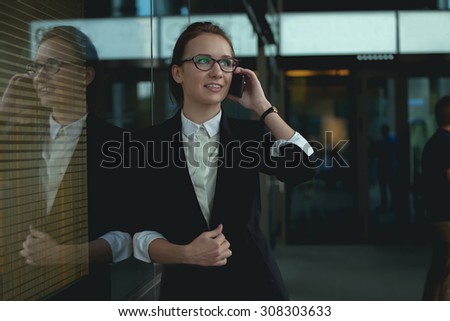 Monan on smart phone - young business woman in office. Casual urban professional manager lady using smartphone smiling happy inside office building