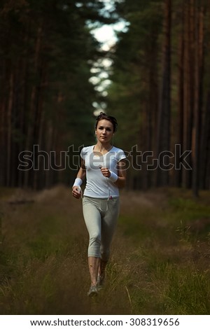 Running woman jogging in  in wooded forest area. Young lady running on forest trail in beautiful nature. Fitness healthy lifestyle concept with female athlete trail runner.