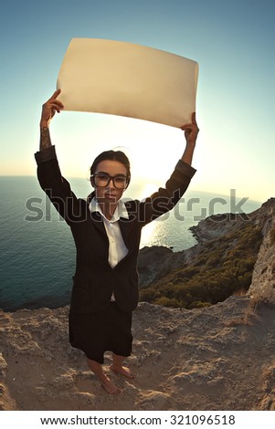 The image of a beautiful young business woman is holding a poster stands on the background of the sea. Young Asian girl on the verge of the boundaries of another state. lens fish eye.