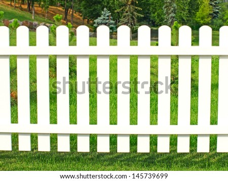 White fence in garden against green grass.