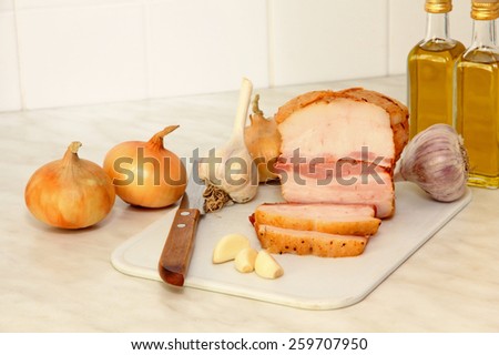 Sliced bacon and vegetables on white kitchen table.