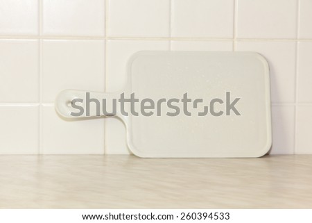 White plastic cutting board with empty space for your menu text on kitchen table.