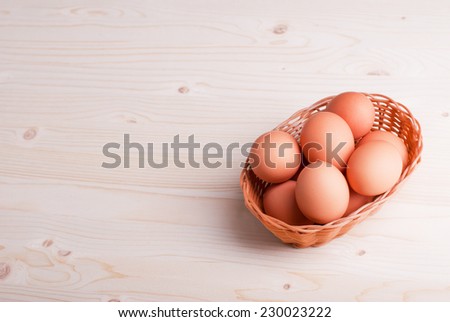 brown eggs in a wicker basket on a light wooden table top view and side view