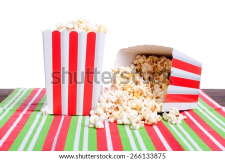 Two boxes of popcorn on the striped napkin, one of them broken up, isolated white background, side view