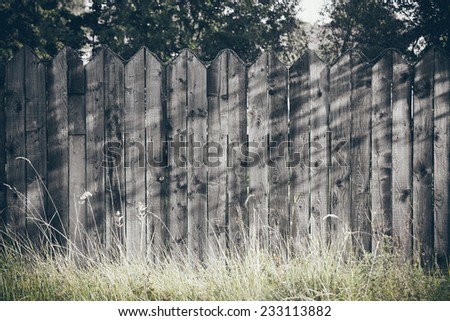 old wooden fence with barbed wire on top. Vintage photography effect. Retro grainy color film look.