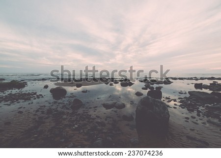 rocky sea beach with wide angle perspective over the sea clouds - retro, vintage style look