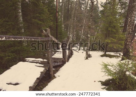 tourist trail in winter forest with snow covered trees in country - aged photo effect, vintage retro
