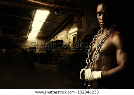 Beautiful and muscular black man with chains in dark background