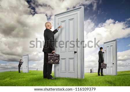 Businessmen or salesmen with briefcases knocking at several doors in a green field