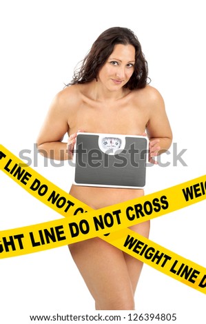 Beautiful nude woman posing with a weight scale behind a \