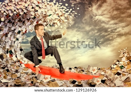 Businessman surfing in a sea made of files and papers