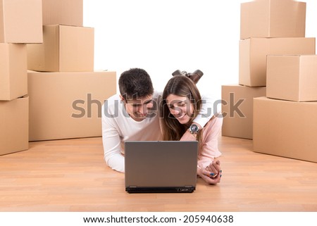 Happy couple with laptop and boxes moving into new home apartment