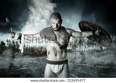 Gladiator or warrior posing with shield and sword outdoors after the battle