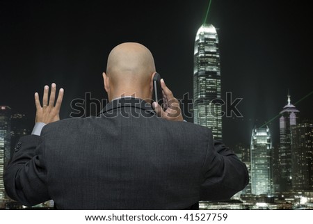 Businessman back making a call by cellphone looking at the busy night city lights