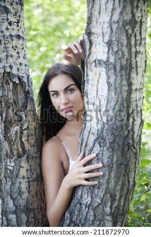 Tanned girl leaned against the trunk of a tree