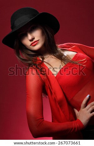 beautiful woman in a hat on a red background. flirty look. Game emotions.