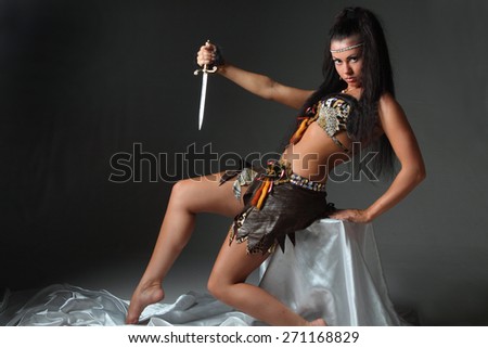 young woman with a knife on a black background. vivid emotions, long beautiful Hair