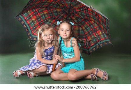 two little girls sitting under a large umbrella, hiding from the rain. friendship and trust