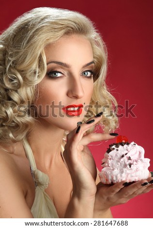 beautiful girl blonde and cake. beautiful long curly hair, bright makeup. red background. plump red lips