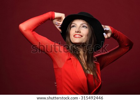 beautiful woman in a hat on a red background. flirty look. Game emotions.