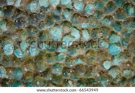 The rough relief of a wall covered with green and blue glaze