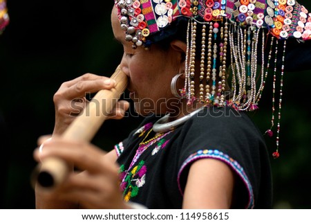 NAN, THAILAND - SEPT 29 : Khmu old woman with traditional clothes and silver  on neck and she used nose playing a bamboo flute in hill  tribe minority village on September 29, 2011 in Nan, Thailand.