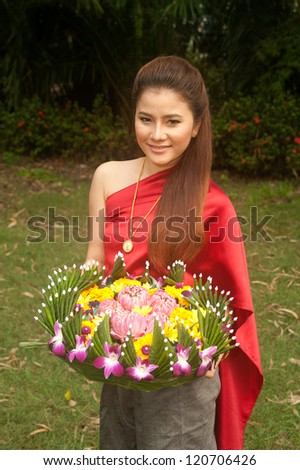 Pretty woman in Thai style clothes in posing hold flower joist.