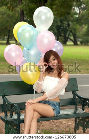 Happy girl  with balloon on a chair in the garden.